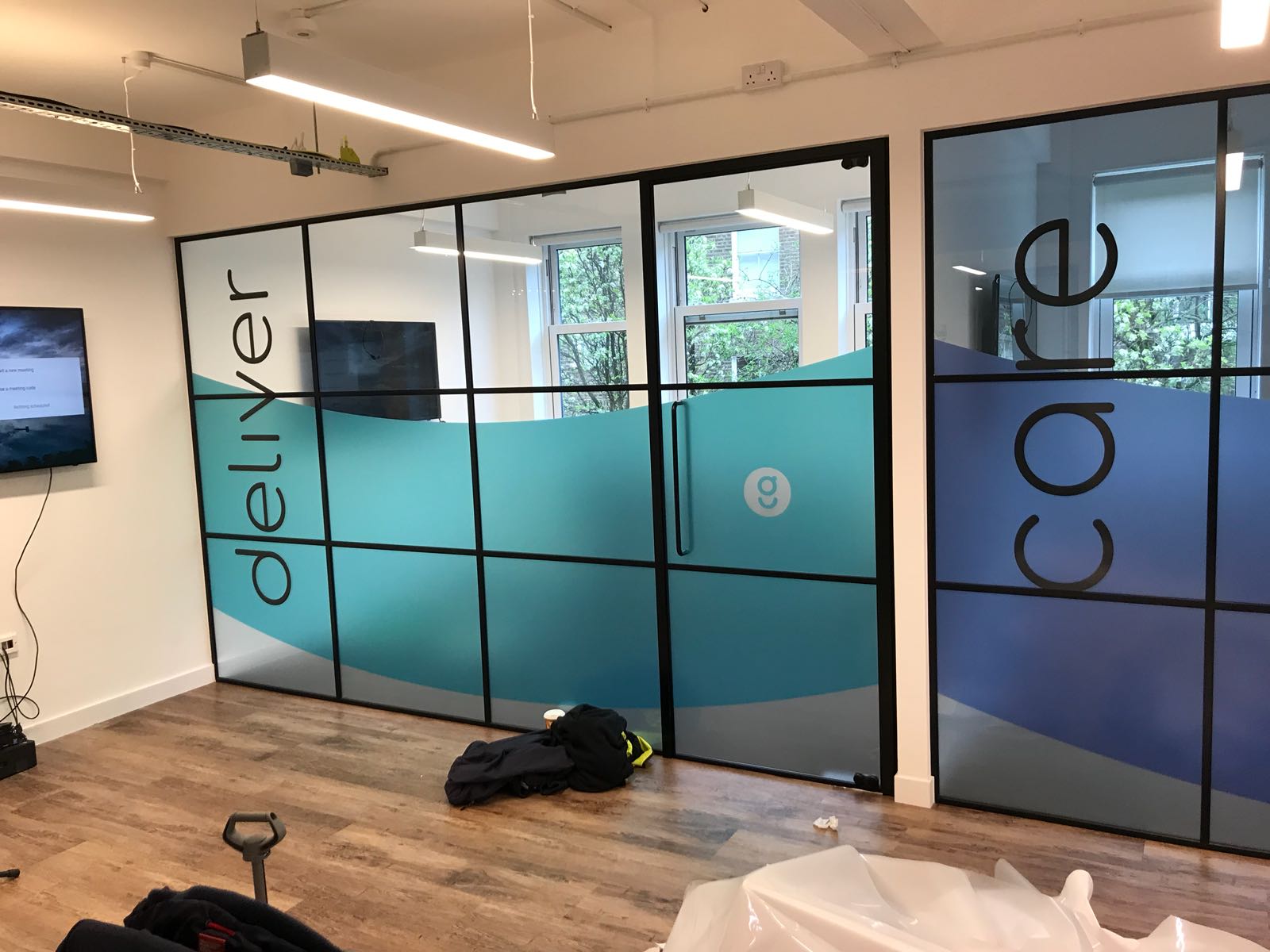 UK Install team fitting branded vinyl graphics to office glass partitions